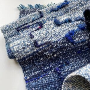 Handgesponnen en handgeweven sjaal in blauw en wit. Met mooie kunstgaren details en een handgeverfde organische indigo schering.