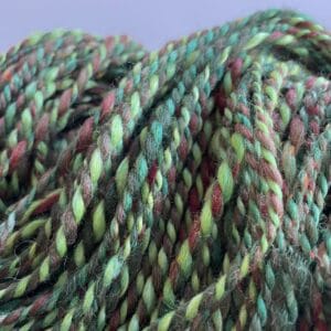 Hand spun Shetland yarn combined with merino and sari silk in forest greens.