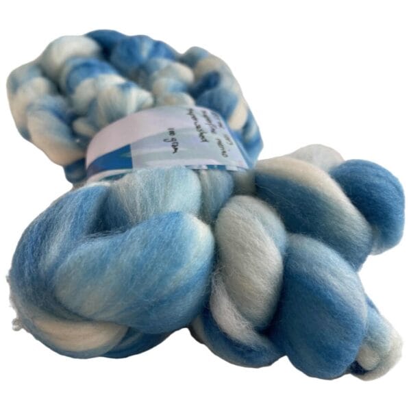 Handgeverfde superwash extra fijne Merino top. Schapenwolkjes. Zacht roving met hemelsblauwe strepen op een witte ondergrond.